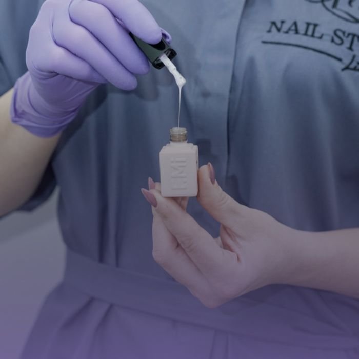Close-up of a beautician mixing nail polish in a modern nail studio.