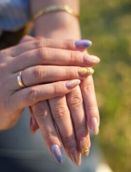Elegant hands showcasing a vibrant multicolored manicure with unique designs.