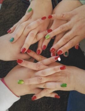 Top view of multiple hands with red and green manicured nails in a festive display.